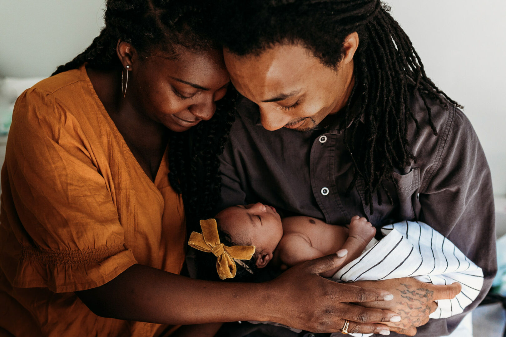 Mom and dad holding a newborn baby while smiling